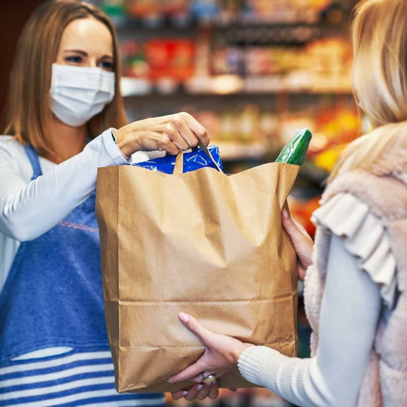 Adult woman in medical mask picking up order in grocery store